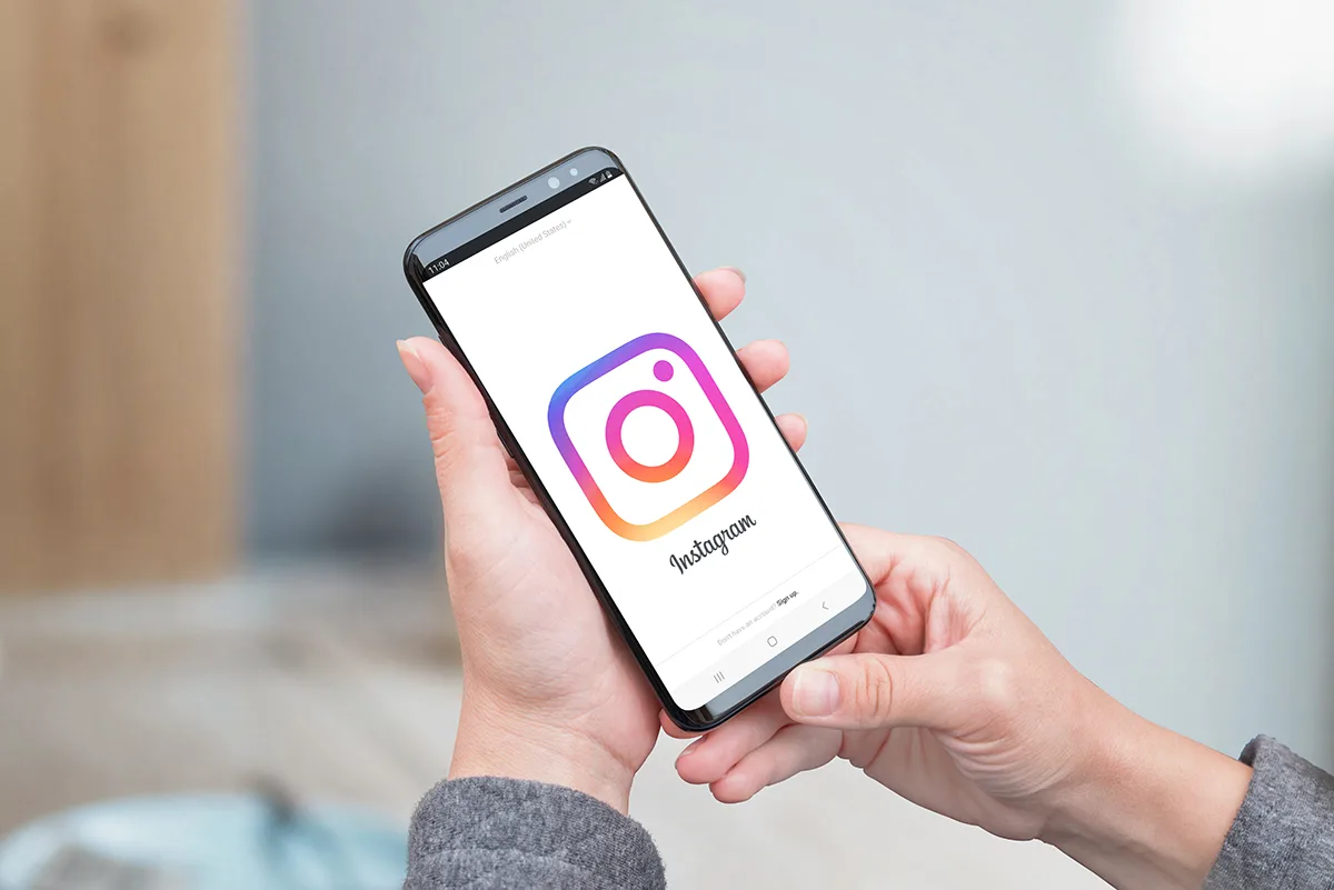 SARAJEVO, BOSNIA AND HERZEGOVINA - JULY 14, 2019: Woman uses instagram application. Large Instagram logo on smartphone display.